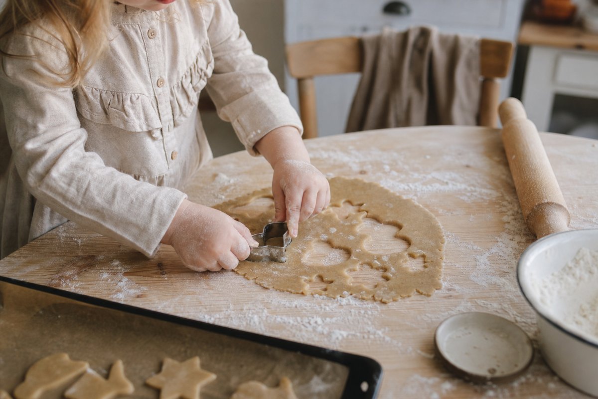 Kinderhände stechen mit einer Ausstechform Kekse aus dem Teig