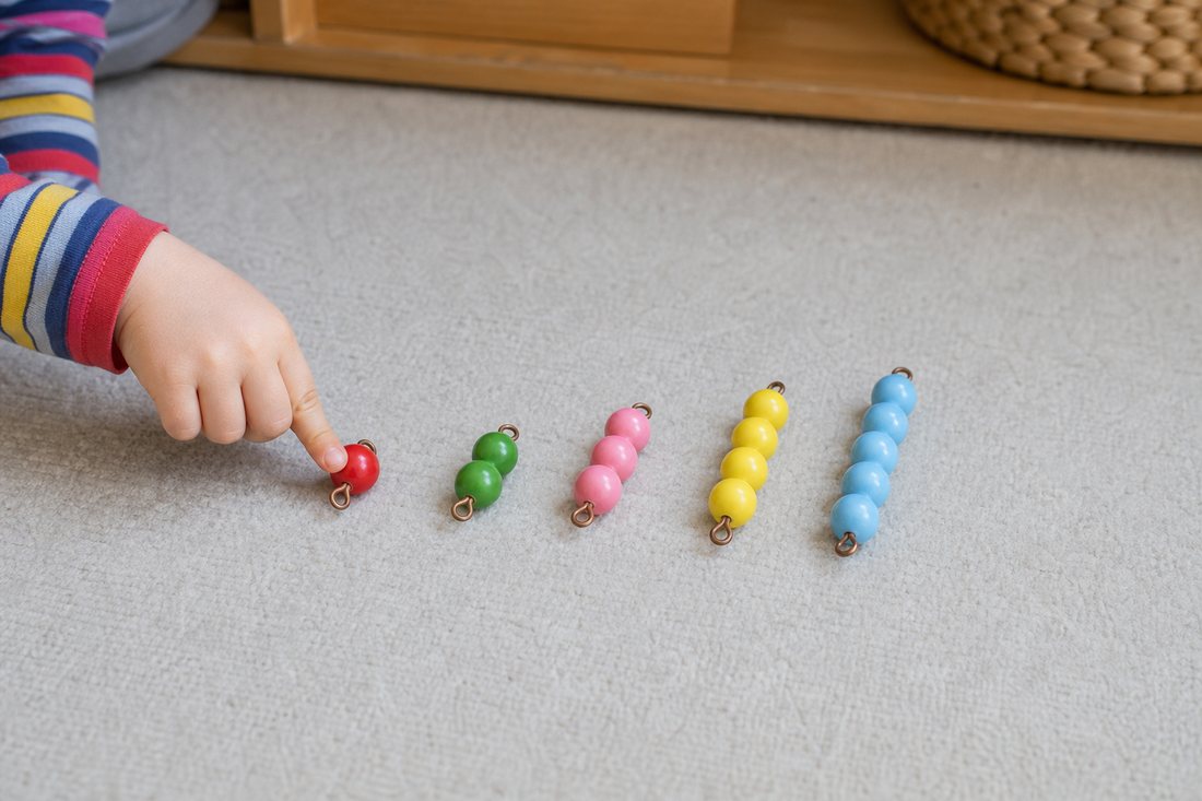 Ein Kind legt Perlenstaebchen in aufsteigender Laenge nebeneinander auf einen Teppich, daneben Ziffernkarten aus Holz.