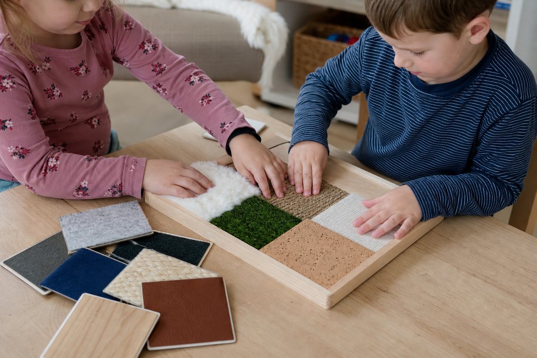 Kinderhaende fahren ueber verschiedene Stoffe und Holzoberflaechen auf einem Tablett, daneben liegen Fuehlkarten mit unt