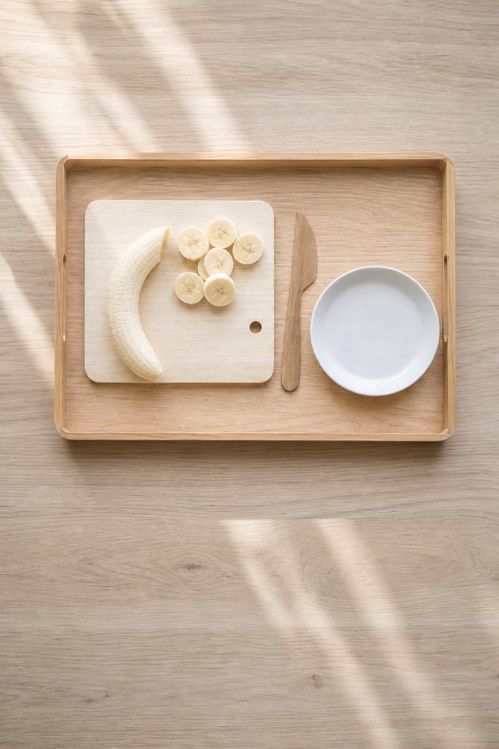 Kleines Schneidebrett mit einer geschälten Banane und Bananenscheiben