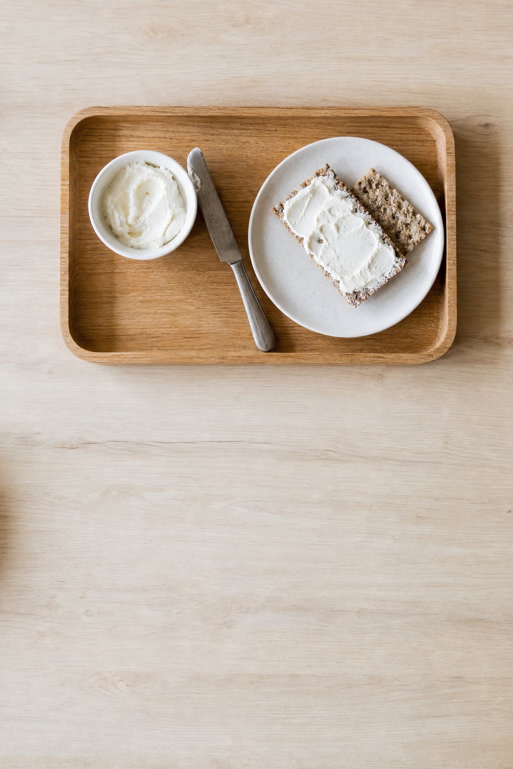 Tablett mit Frischkäse, stumpfem Streichmesser und Knäckebrot