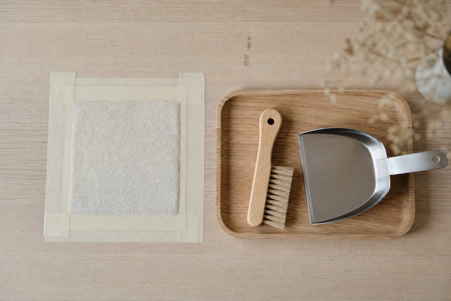 Draufsicht auf einen hellen Holztisch, darauf ein mit hellem Malerkrepp abgeklebtes Quadrat, in dem etwas Griess liegt, daneb