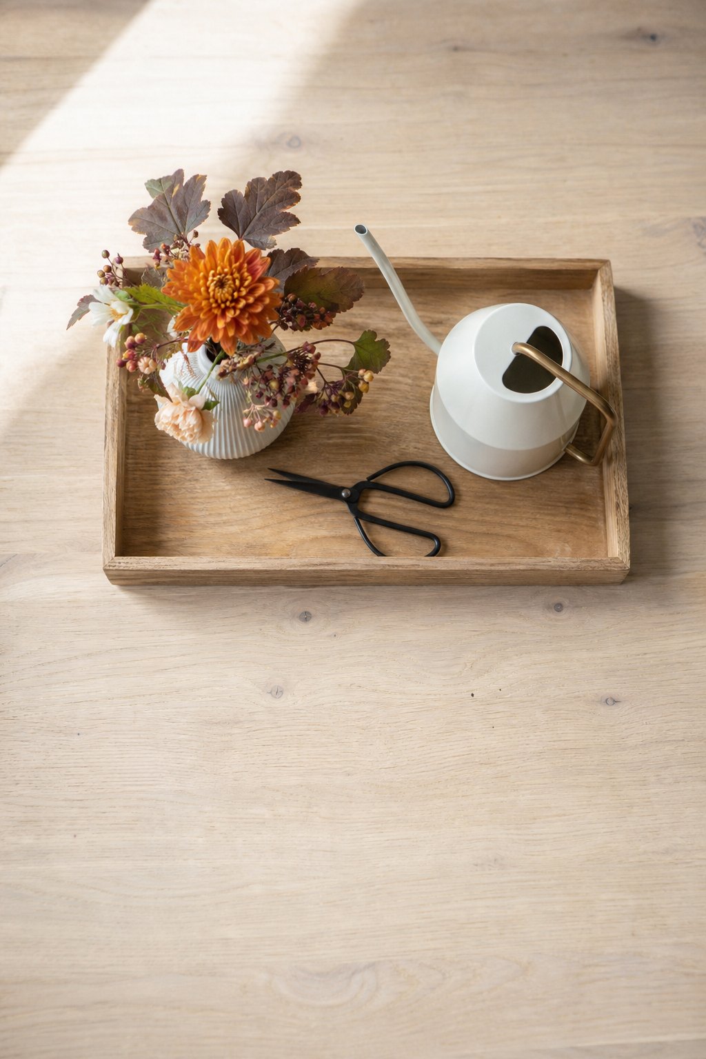 Kleine Vase, Herbstblumen, Schere und Wasserkännchen auf einem Tablett
