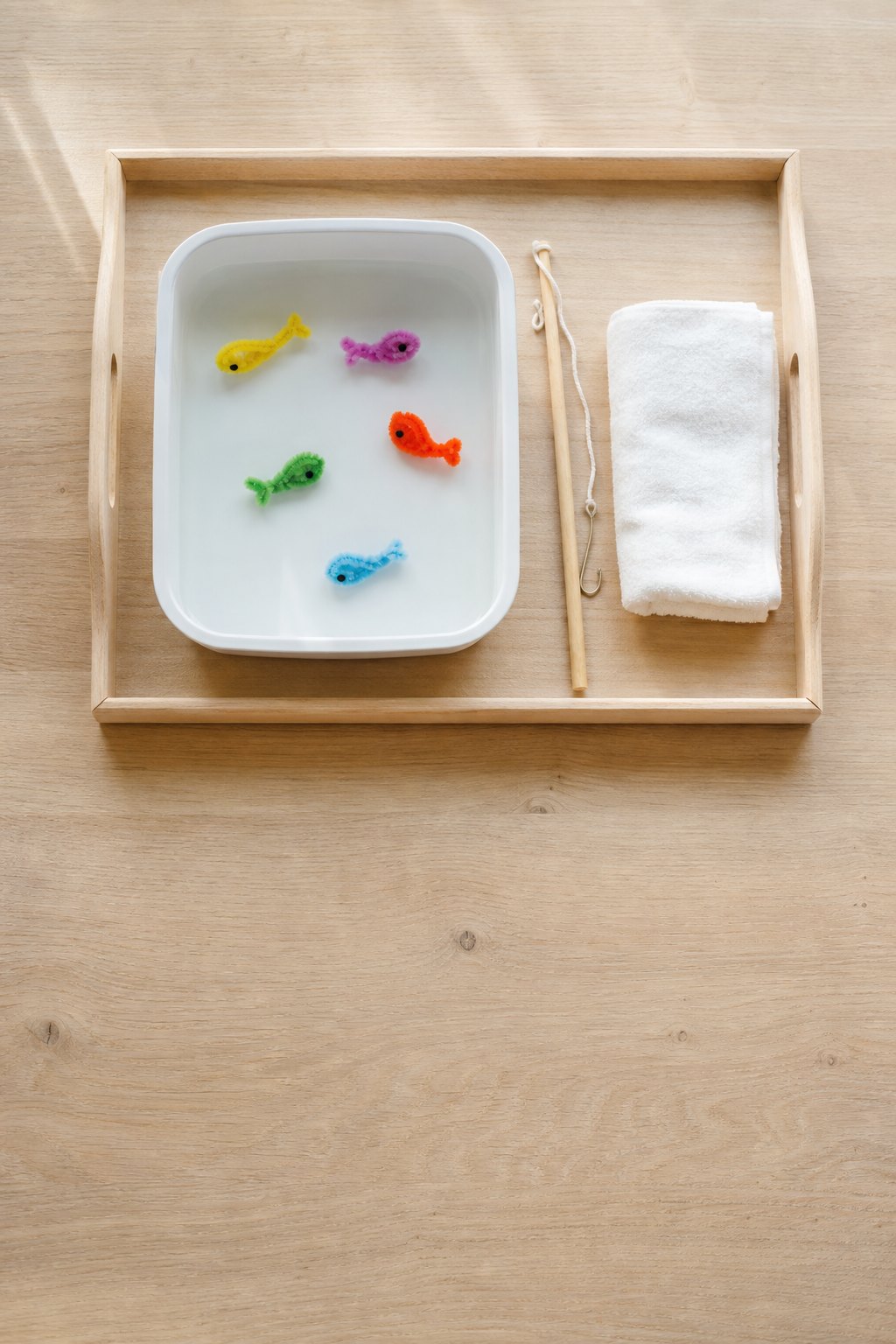 Tablett mit einer flachen Form voll Wasser, in der kleine bunte Fische schwimmen