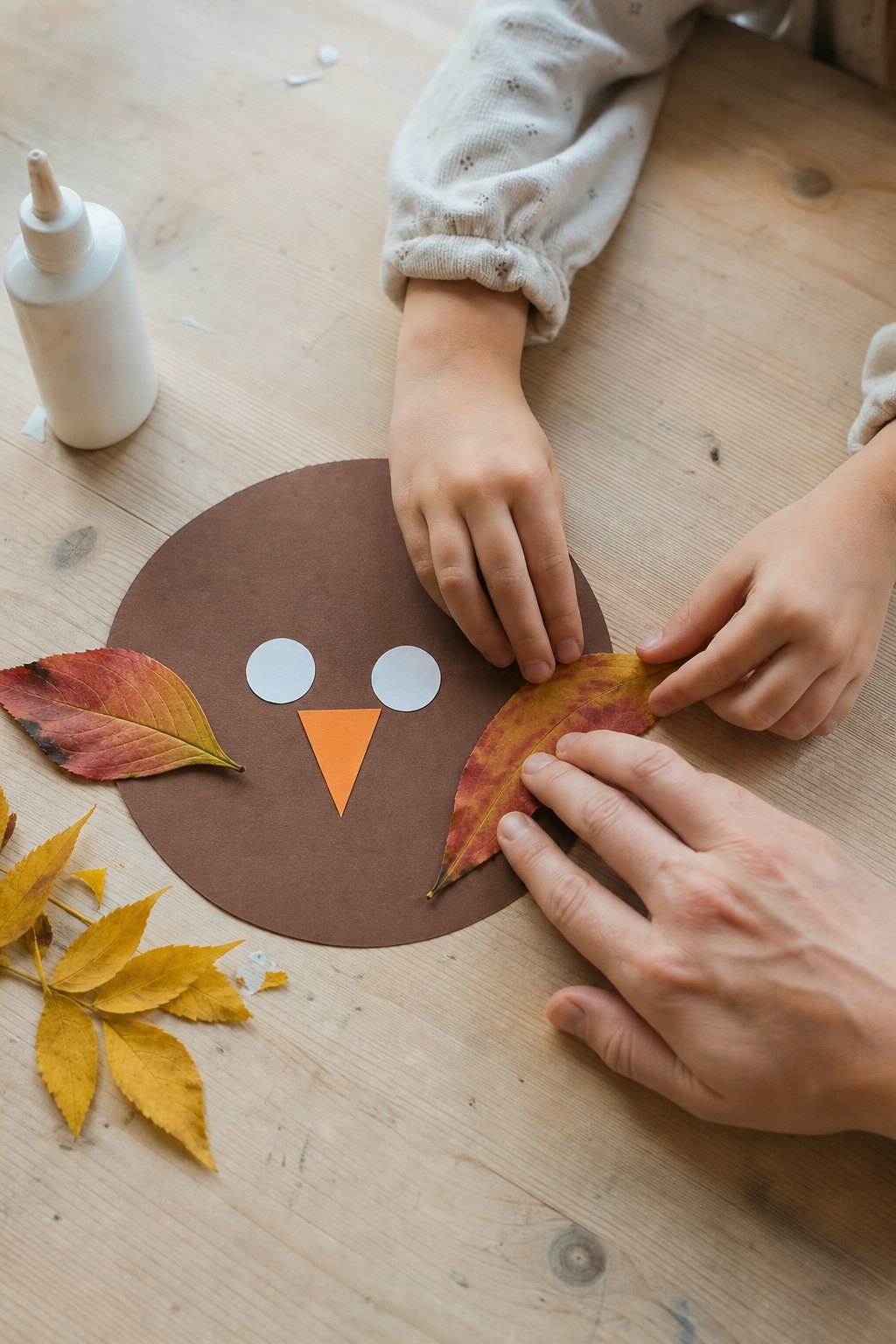 Kinderhände drücken ein Herbstblatt als Flügel an den braunen Eulenkörper