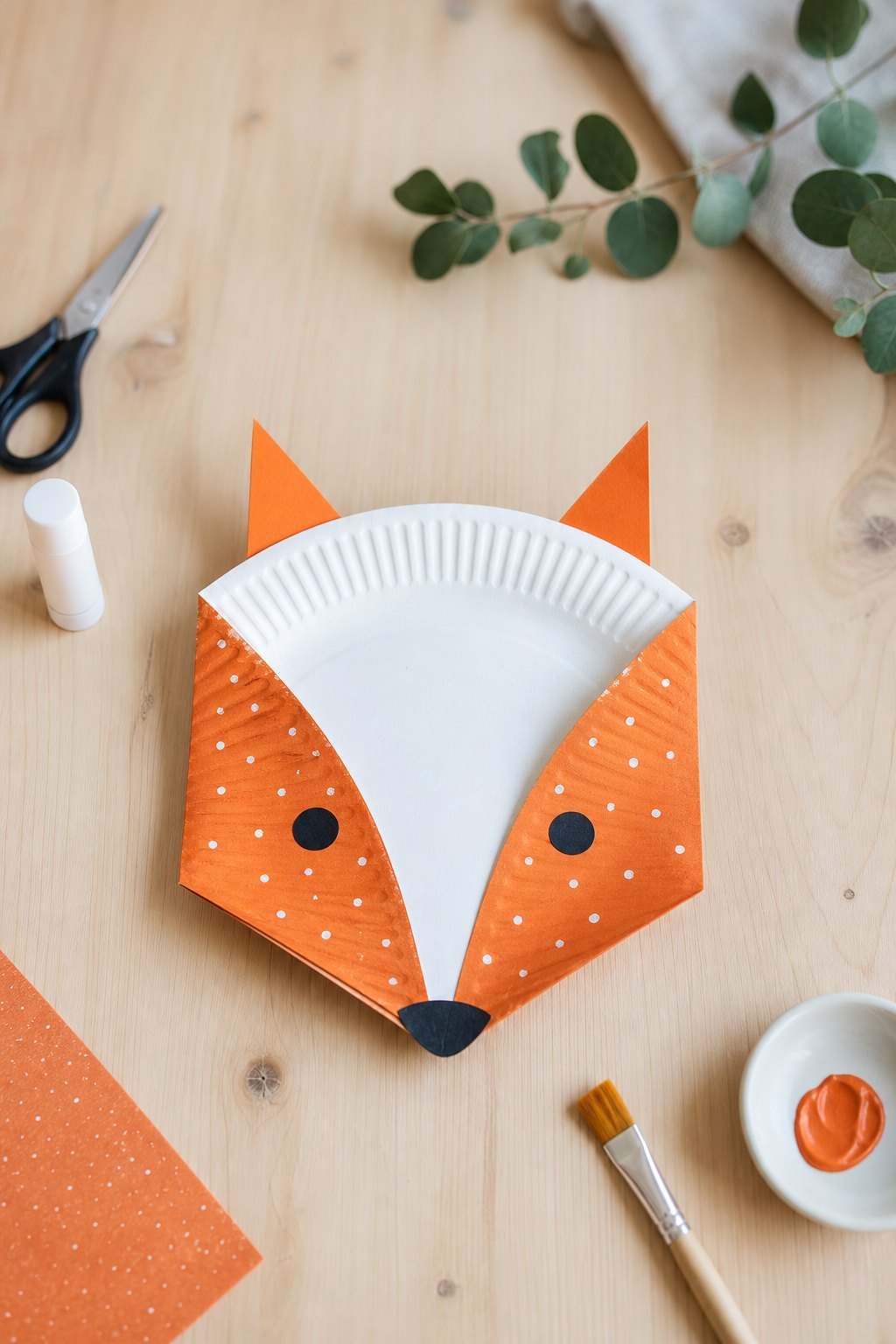 Der Fuchs aus dem Pappteller — Ein Fuchsgesicht aus einem Pappteller auf einem hellen Holztisch, von oben fotografiert