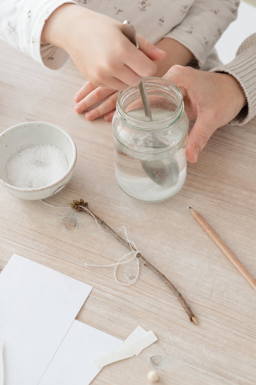 Kinderhand rührt Salz in ein Glas mit warmem Wasser