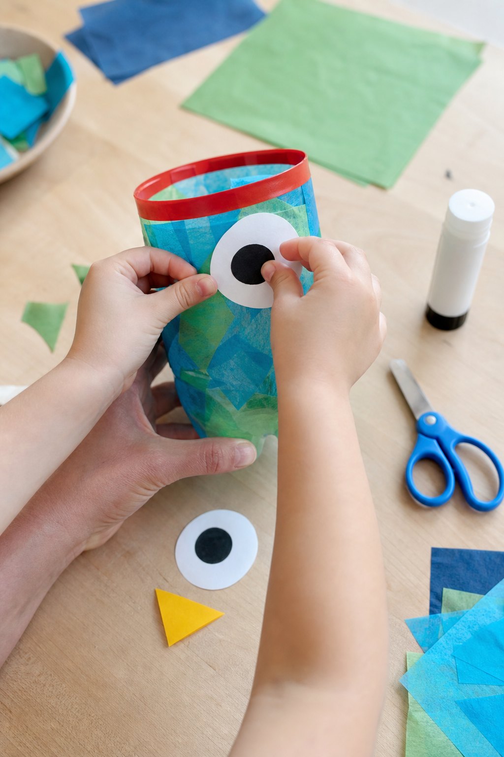 Kinderhände kleben die Papieraugen auf die Flaschen-Eule