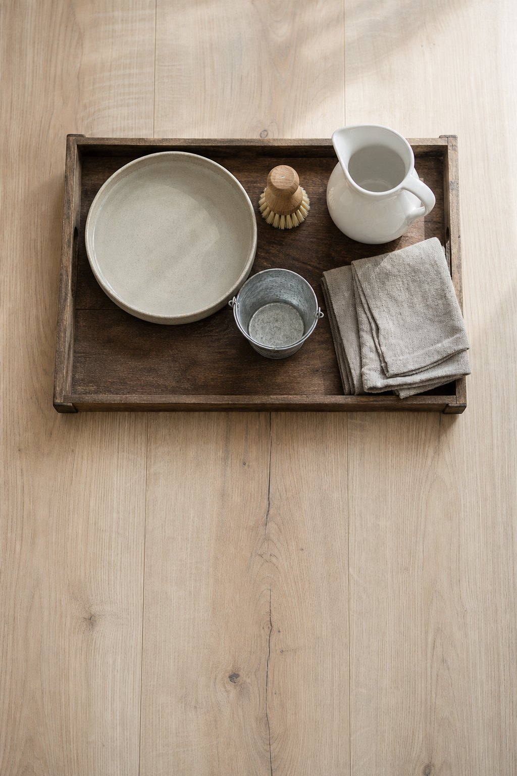 Ein dunkles Holztablett von oben fotografiert, darauf eine flache runde Tonschale mit klarem Wasser, daneben eine kleine Spue